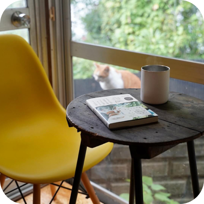 写真:テーブルの上にホントコーヒーが置いてあります。奥に猫がいます。