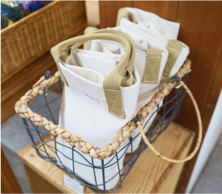 写真:かごの中に白いトートバッグが3つ並んでいます