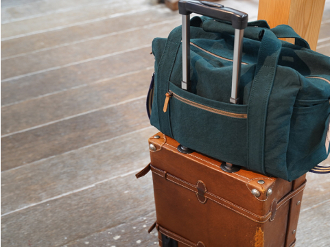 写真:退路いスーツケースの上に、濃い緑色のバッグが乗っています
